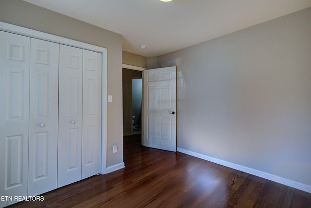 unfurnished bedroom featuring a closet, baseboards, and dark wood finished floors