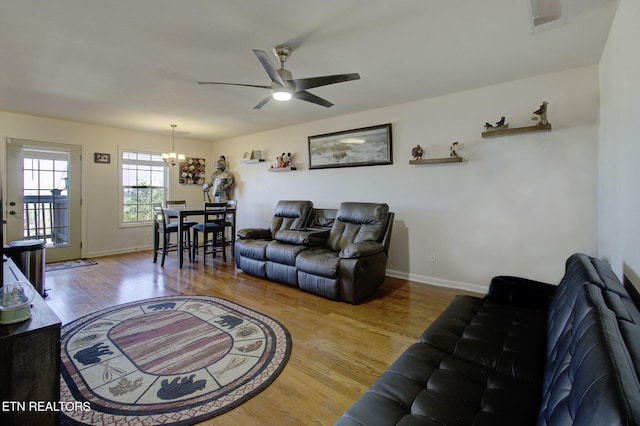 living room featuring baseboards, wood finished floors, and ceiling fan with notable chandelier