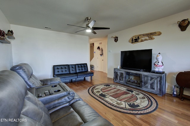 living area with ceiling fan, visible vents, and wood finished floors