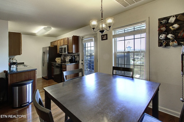 dining space featuring an inviting chandelier, dark wood-style floors, visible vents, and baseboards