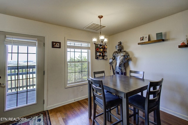 dining room featuring an inviting chandelier, baseboards, visible vents, and dark wood-style flooring