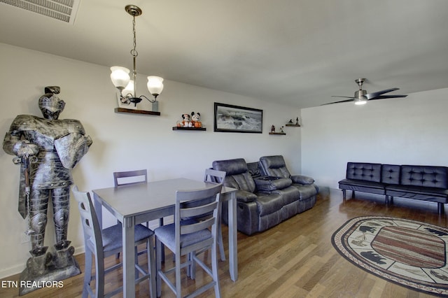 dining space with visible vents, wood finished floors, and ceiling fan with notable chandelier