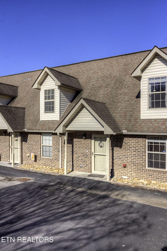 view of front of house with brick siding and roof with shingles