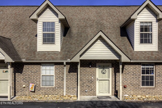 view of front facade with brick siding and roof with shingles