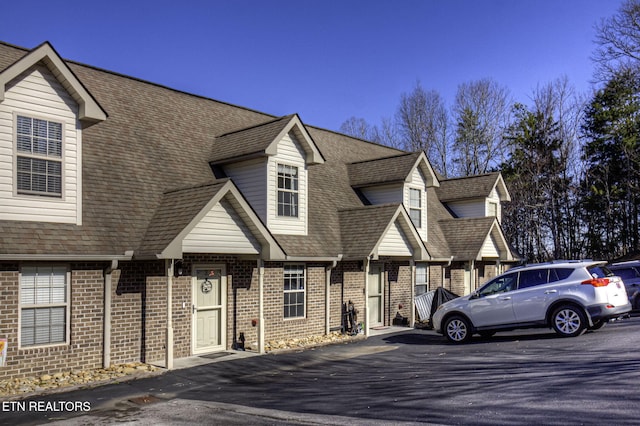 view of front of property with brick siding and roof with shingles