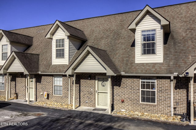 view of front of property with brick siding and a shingled roof