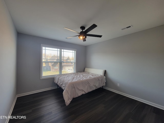 bedroom with ceiling fan, visible vents, baseboards, and dark wood finished floors