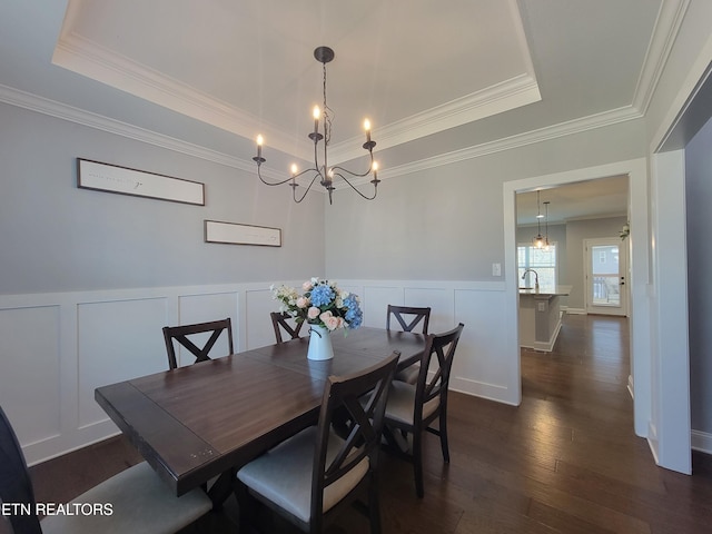 dining space with a raised ceiling, dark wood-type flooring, and a chandelier