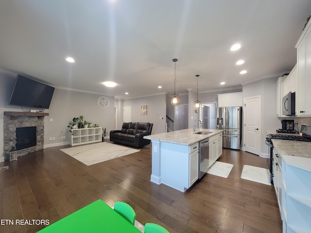 kitchen with dark wood-type flooring, a sink, open floor plan, stainless steel appliances, and a fireplace