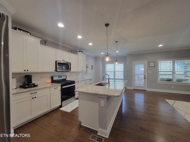 kitchen featuring visible vents, crown molding, decorative backsplash, appliances with stainless steel finishes, and a sink