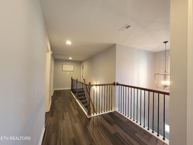 hallway with dark wood-style floors, visible vents, an upstairs landing, and baseboards