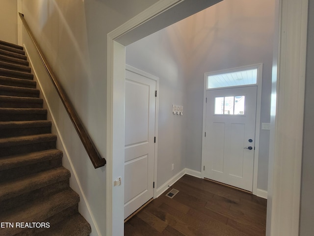 foyer featuring stairway, baseboards, visible vents, and dark wood-style flooring