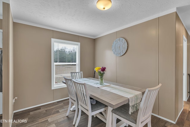 dining area featuring baseboards, a textured ceiling, wood finished floors, and crown molding