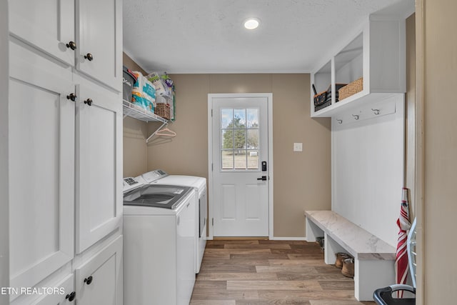 clothes washing area featuring cabinet space, a textured ceiling, independent washer and dryer, and wood finished floors