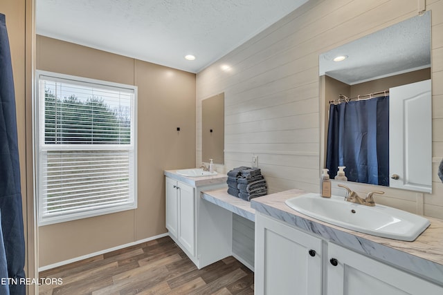 full bath featuring baseboards, vanity, a shower with curtain, wood finished floors, and a textured ceiling