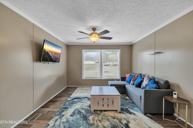 living room with dark wood-type flooring, crown molding, a ceiling fan, and a textured ceiling