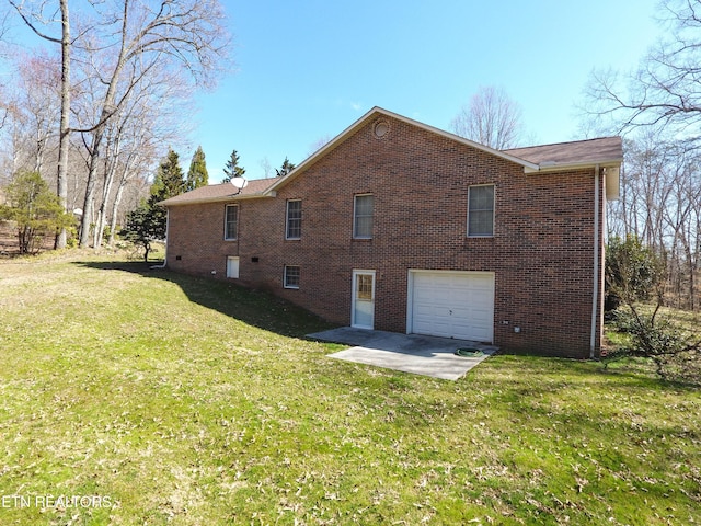 back of property with a garage, a lawn, brick siding, and driveway