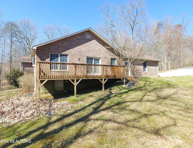 back of house with a deck, a lawn, and brick siding