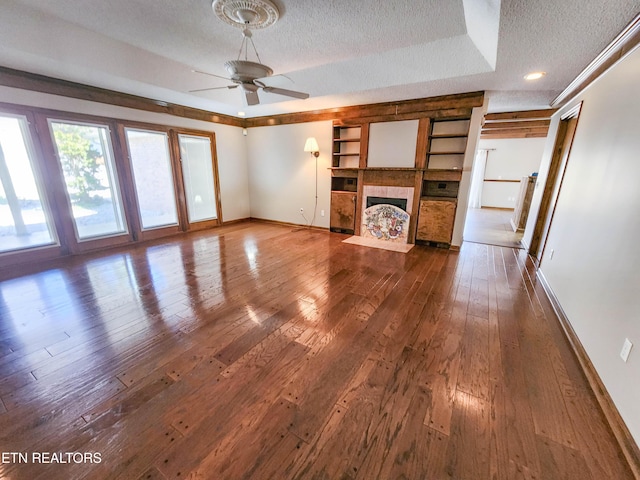 unfurnished living room featuring a tile fireplace, a textured ceiling, baseboards, and hardwood / wood-style flooring