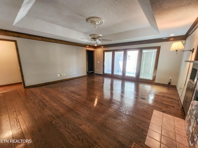 unfurnished living room with a tiled fireplace, a raised ceiling, wood-type flooring, and a textured ceiling