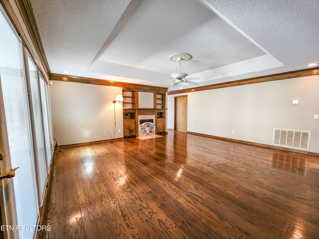 unfurnished living room with visible vents, a tile fireplace, a raised ceiling, and wood-type flooring