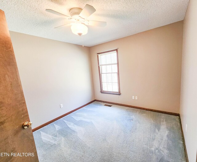 carpeted empty room featuring visible vents, ceiling fan, a textured ceiling, and baseboards