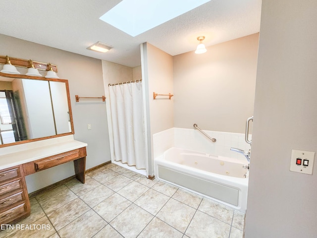 bathroom with tile patterned floors, a textured ceiling, a jetted tub, a skylight, and vanity