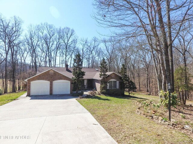 view of front of property with concrete driveway, a front yard, a garage, brick siding, and a chimney