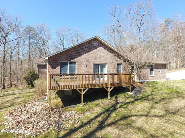 rear view of house with a wooden deck, brick siding, and a lawn