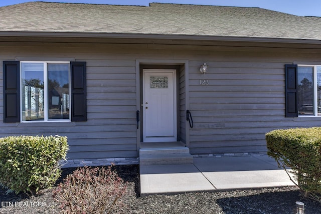 doorway to property with a shingled roof