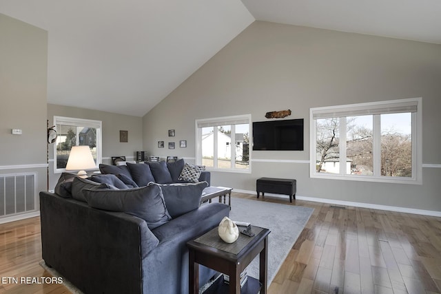 living area featuring visible vents, baseboards, high vaulted ceiling, and wood finished floors