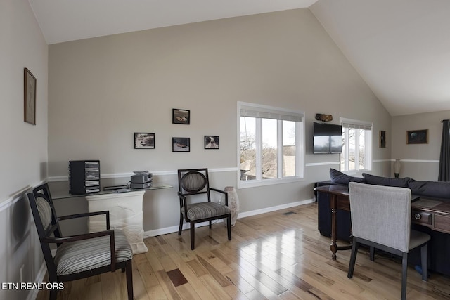 office area featuring baseboards, high vaulted ceiling, and wood finished floors