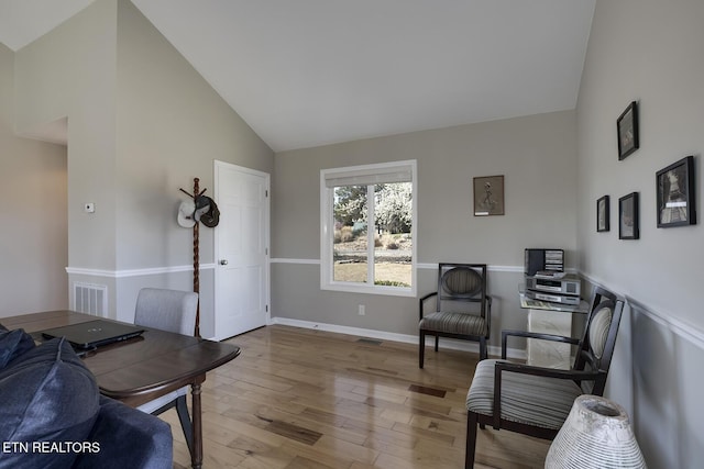 office area featuring light wood finished floors, visible vents, high vaulted ceiling, and baseboards