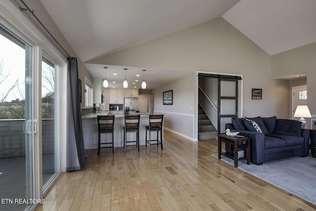 living room with recessed lighting, stairway, high vaulted ceiling, and light wood finished floors