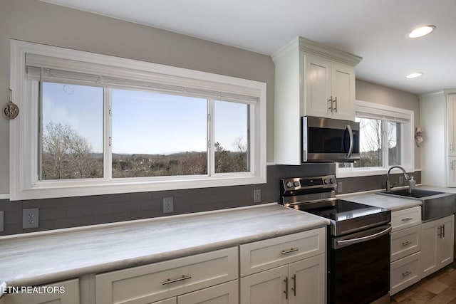 kitchen with a sink, decorative backsplash, white cabinets, and stainless steel appliances