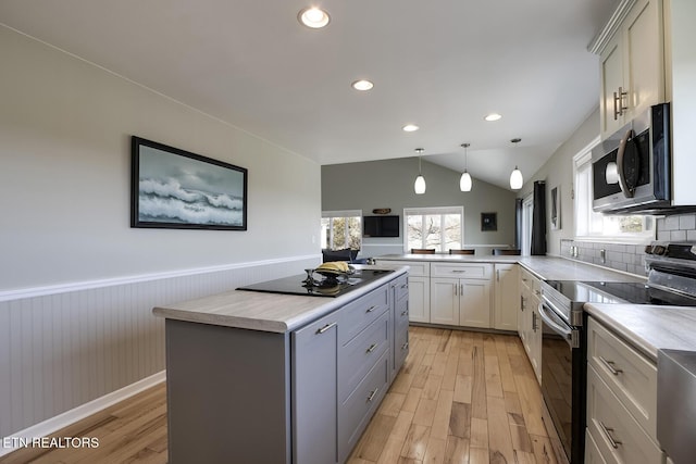 kitchen with a wainscoted wall, appliances with stainless steel finishes, light wood-type flooring, and light countertops