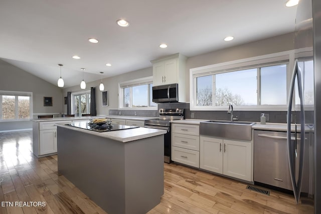 kitchen with visible vents, light wood-style flooring, a sink, appliances with stainless steel finishes, and a peninsula