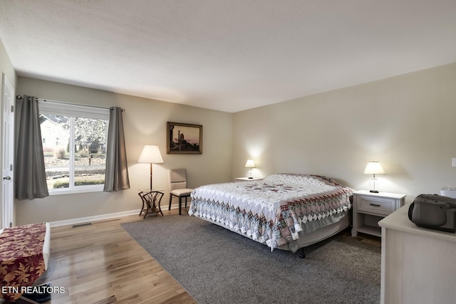 bedroom featuring visible vents, baseboards, and wood finished floors