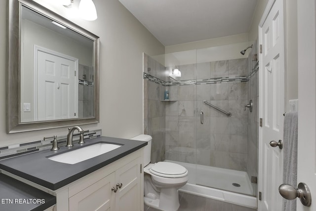 full bath featuring toilet, a stall shower, and vanity