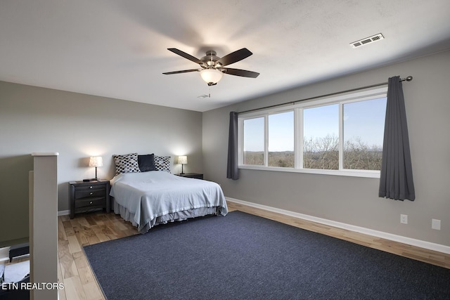 bedroom with visible vents, baseboards, and light wood finished floors