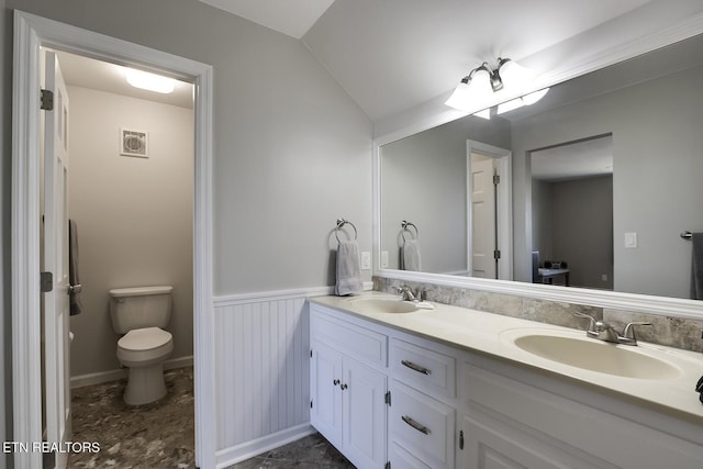 full bathroom featuring lofted ceiling, toilet, a wainscoted wall, and a sink