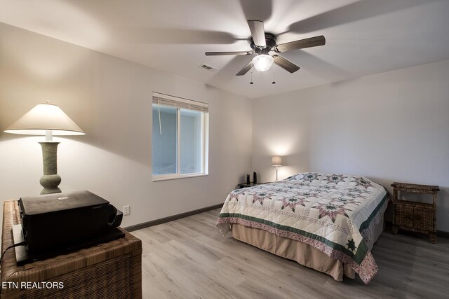 bedroom with a ceiling fan, wood finished floors, visible vents, and baseboards