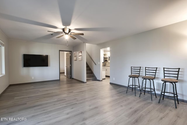 interior space featuring stairs, baseboards, light wood-type flooring, and ceiling fan