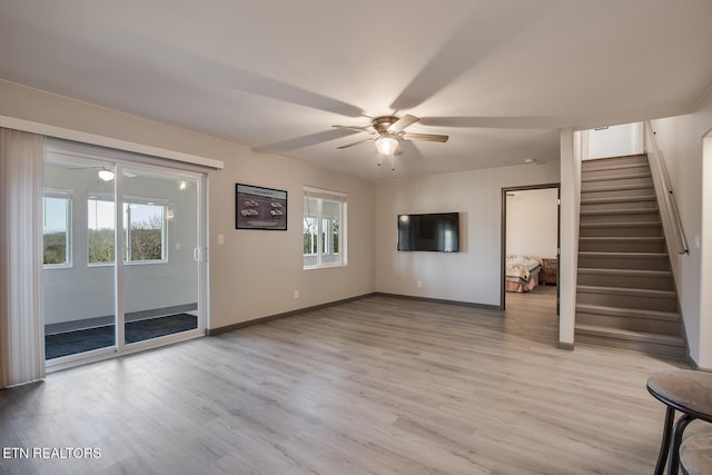 unfurnished living room featuring light wood-style flooring, stairs, and a ceiling fan