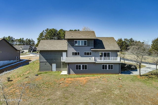 rear view of property featuring a yard and roof with shingles