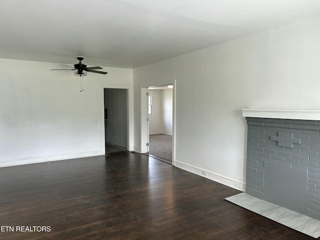 unfurnished living room featuring a brick fireplace, baseboards, ceiling fan, and wood finished floors