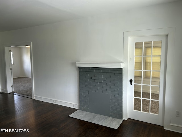 unfurnished living room with baseboards, wood finished floors, and a fireplace