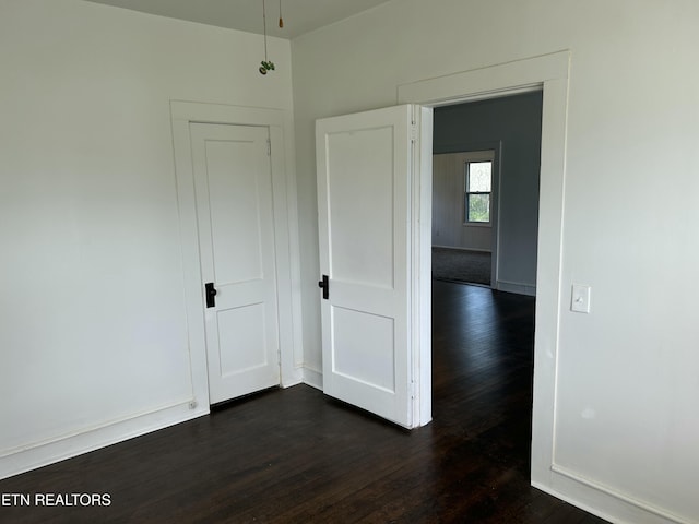 spare room featuring dark wood finished floors and baseboards