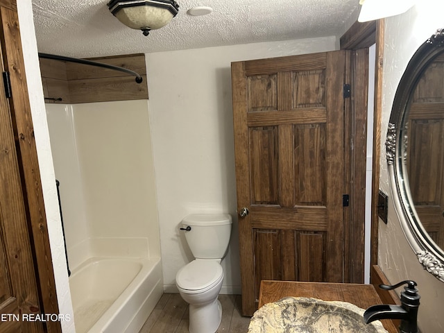 full bathroom with a textured ceiling, toilet, shower / bathtub combination, and a sink