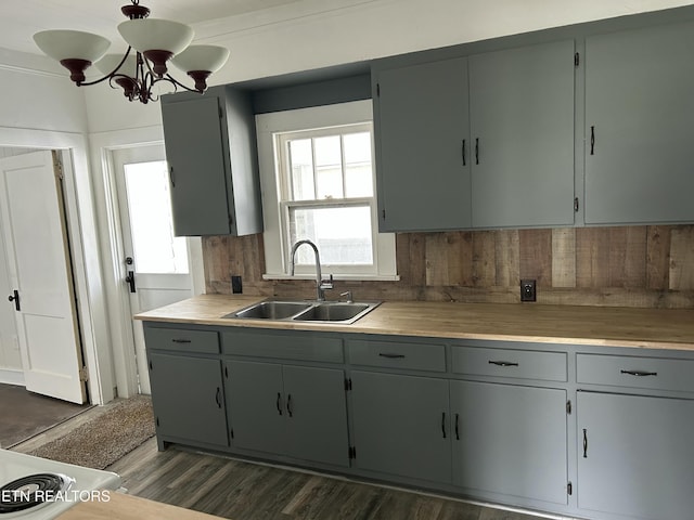 kitchen with a sink, decorative backsplash, dark wood-type flooring, light countertops, and crown molding